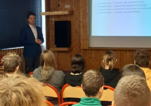 Pan Michał Hankiewicz w trakcie prowadzenia prelekcji oraz uczniów XLII LO im. Ireny Sendlerowej w Sali kinowej naszej szkoły.