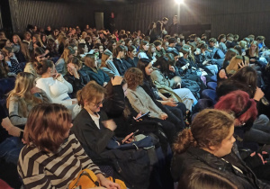 Duża grupa uczniów siedzących w teatrze.