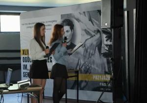 Uczennice na tle baneru z patronką szkoły