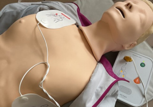 Manekin treningowy wraz z defibrylatorem.